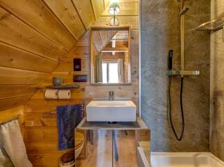 This charming bathroom features a unique wooden sloped ceiling, creating a cozy and inviting atmosphere.