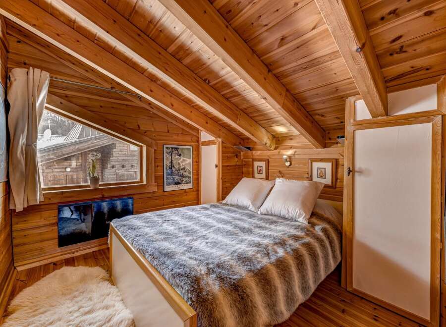 Step into this cozy bedroom retreat, featuring stunning wooden accents and a unique sloped ceiling.