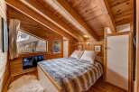 Step into this cozy bedroom retreat, featuring stunning wooden accents and a unique sloped ceiling.