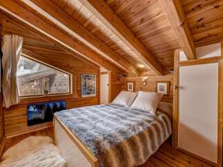 Step into this cozy bedroom retreat, featuring stunning wooden accents and a unique sloped ceiling.