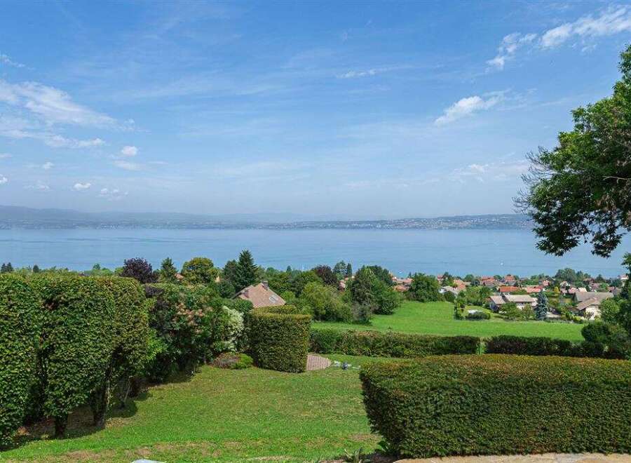 Enjoy breathtaking views from this stunning property! This home features lush greenery, manicured hedges, and a serene lake backdrop.
