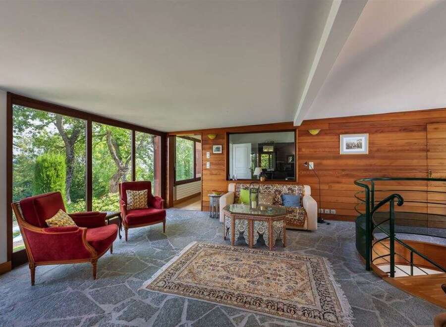Experience luxury living in this stunning property, featuring a bright and airy living room with floor-to-ceiling windows that offer breathtaking views of the surrounding greenery.