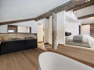 This stunning property features a luxurious bathroom with a sleek black vanity and dual sinks, complemented by rustic wooden beams that add character.