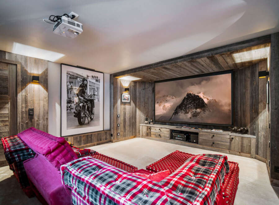 Experience luxury living in this stunning home theater! Featuring a large screen, comfortable seating, and rustic wood accents, this space is perfect for movie nights.