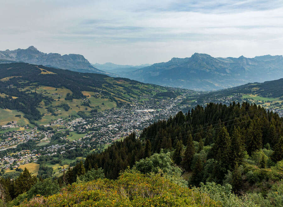 Discover breathtaking panoramic views from this elevated property, overlooking a charming alpine village nestled amidst rolling green hills and majestic mountains.