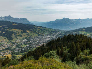 Discover breathtaking panoramic views from this elevated property, overlooking a charming alpine village nestled amidst rolling green hills and majestic mountains.