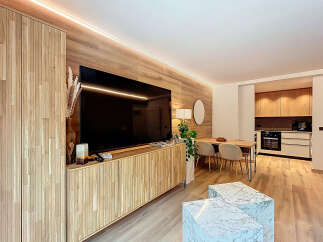 Experience modern living in this stylish property, featuring a sleek entertainment center with a large TV and custom cabinetry.