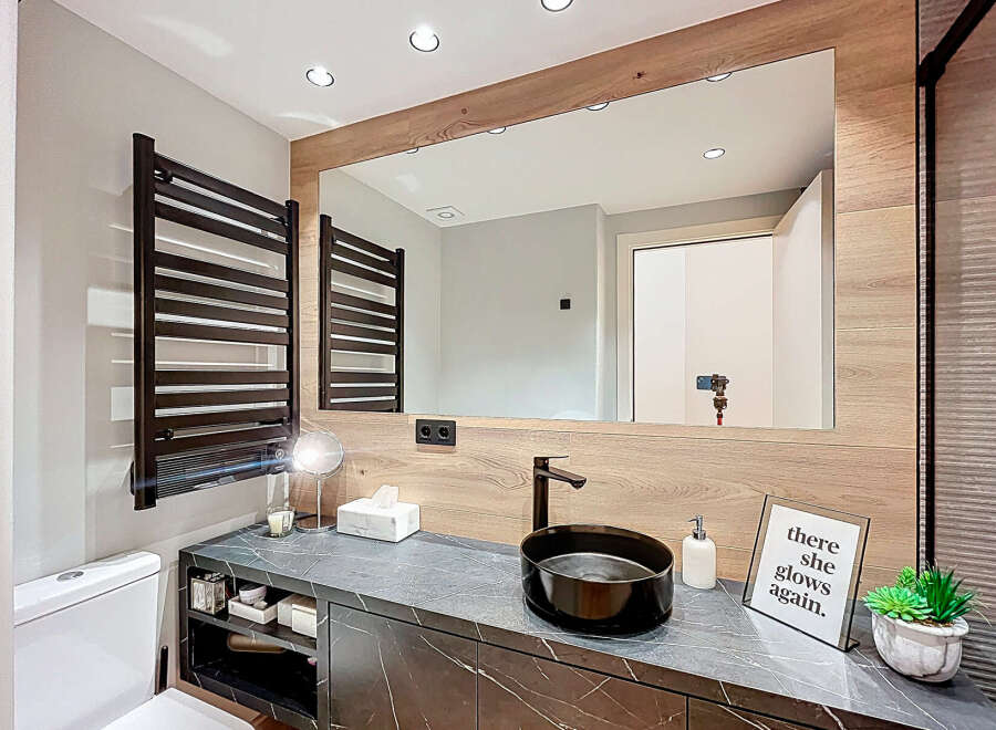 This modern bathroom boasts a sleek design with a dark marble countertop and a stylish black sink.