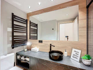 This modern bathroom boasts a sleek design with a dark marble countertop and a stylish black sink.