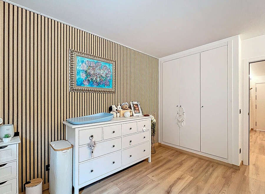 This charming nursery features a stylish design with a wooden accent wall and a bright, airy feel.