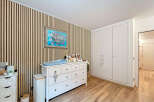 This charming nursery features a stylish design with a wooden accent wall and a bright, airy feel.