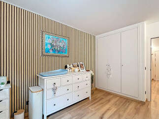 This charming nursery features a stylish design with a wooden accent wall and a bright, airy feel.