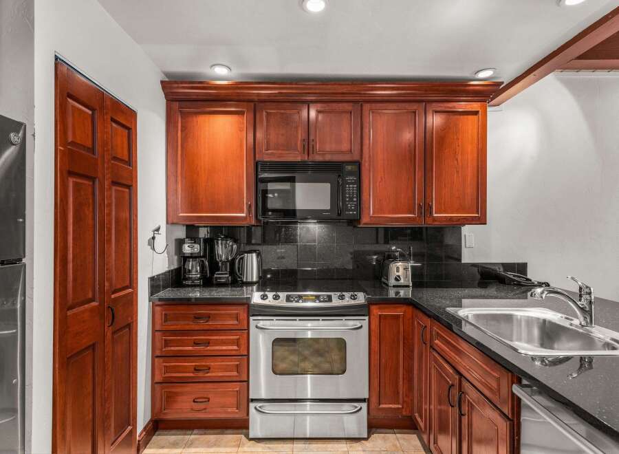 This stunning kitchen boasts rich, wooden cabinetry and sleek, black countertops, creating a warm and inviting atmosphere.