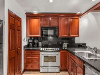 This stunning kitchen boasts rich, wooden cabinetry and sleek, black countertops, creating a warm and inviting atmosphere.
