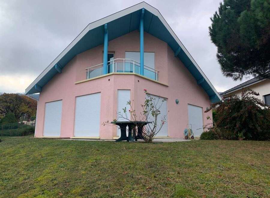 This charming property boasts a unique architectural design with a distinctive pink exterior and a striking blue roof.