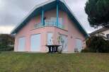This charming property boasts a unique architectural design with a distinctive pink exterior and a striking blue roof.
