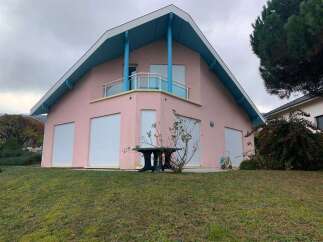 This charming property boasts a unique architectural design with a distinctive pink exterior and a striking blue roof.