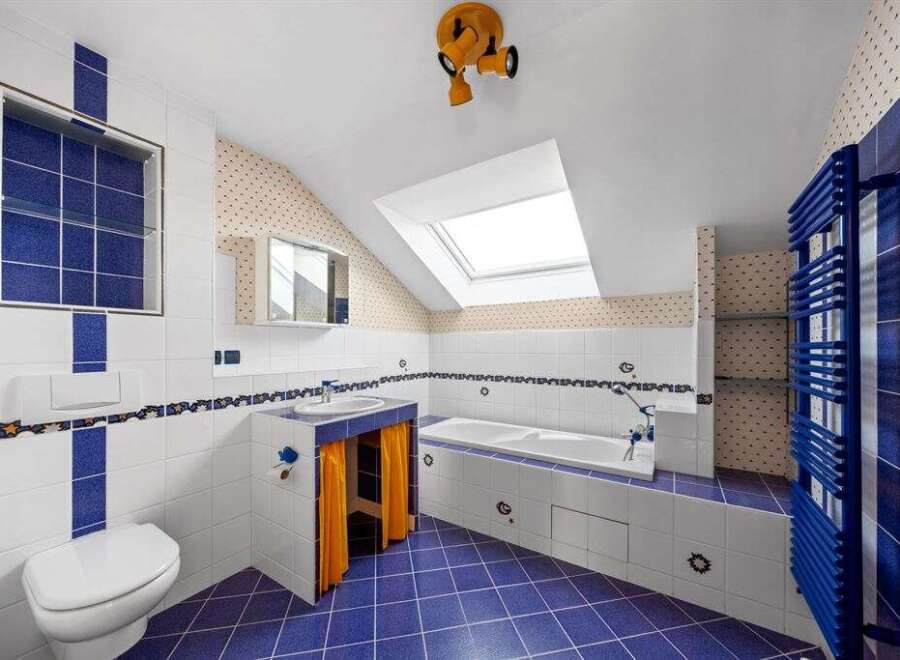 This unique bathroom boasts a vibrant blue and white tile design, creating a fresh and inviting atmosphere.