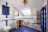 This unique bathroom boasts a vibrant blue and white tile design, creating a fresh and inviting atmosphere.