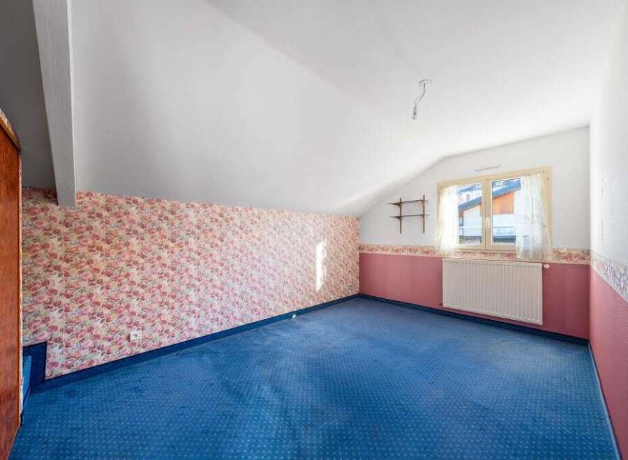 Discover the charm of this unique property! This room features a cozy atmosphere with its floral wallpaper and blue carpet.