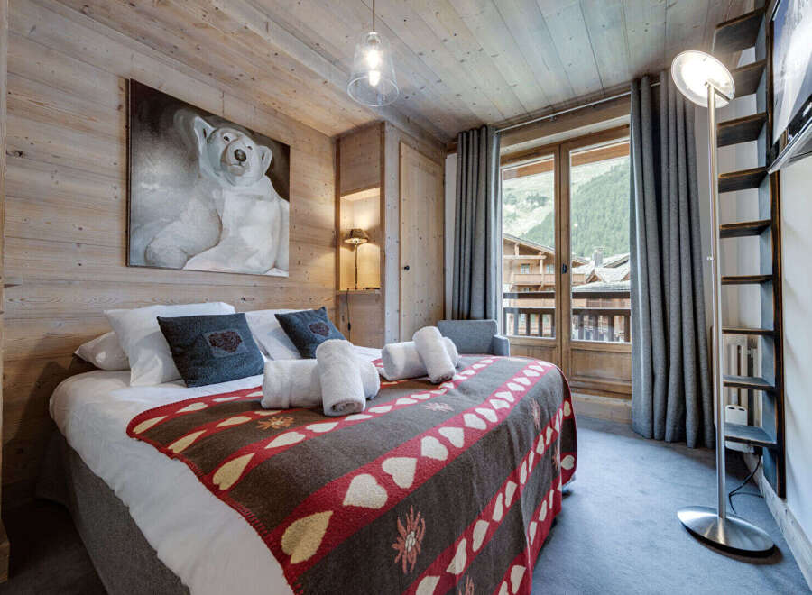 Experience the charm of this cozy bedroom, featuring a rustic wooden interior and a comfortable bed adorned with a unique patterned blanket.