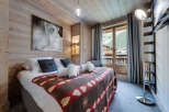 Experience the charm of this cozy bedroom, featuring a rustic wooden interior and a comfortable bed adorned with a unique patterned blanket.