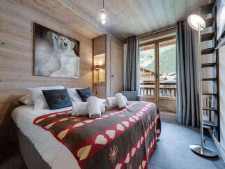 Experience the charm of this cozy bedroom, featuring a rustic wooden interior and a comfortable bed adorned with a unique patterned blanket.