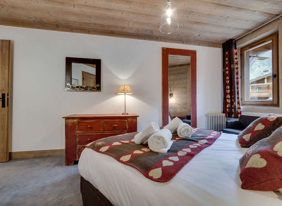 Experience the charm of this cozy bedroom, featuring a rustic wooden ceiling and a warm, inviting ambiance.
