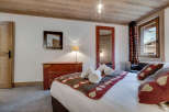 Experience the charm of this cozy bedroom, featuring a rustic wooden ceiling and a warm, inviting ambiance.