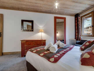 Experience the charm of this cozy bedroom, featuring a rustic wooden ceiling and a warm, inviting ambiance.