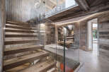 This stunning property showcases a modern interior with a rustic touch, featuring a beautifully crafted wooden staircase with glass railings.