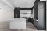 This modern kitchen boasts sleek, dark cabinetry complemented by bright white countertops and a spacious island, perfect for meal preparation and entertaining.