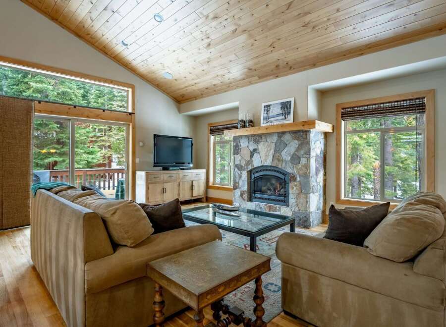 Experience the warmth of this stunning living room, featuring a cozy fireplace and a beautiful wooden ceiling.