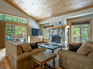 Experience the warmth of this stunning living room, featuring a cozy fireplace and a beautiful wooden ceiling.