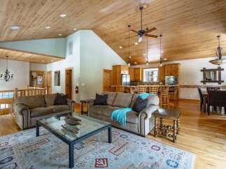 This stunning property boasts a spacious open-concept living area with a beautiful wooden ceiling and hardwood floors.