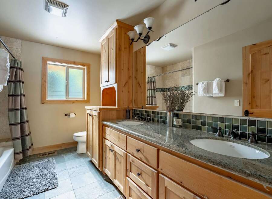 This stunning bathroom features a beautiful wooden vanity with ample storage and a granite countertop, providing both style and functionality.
