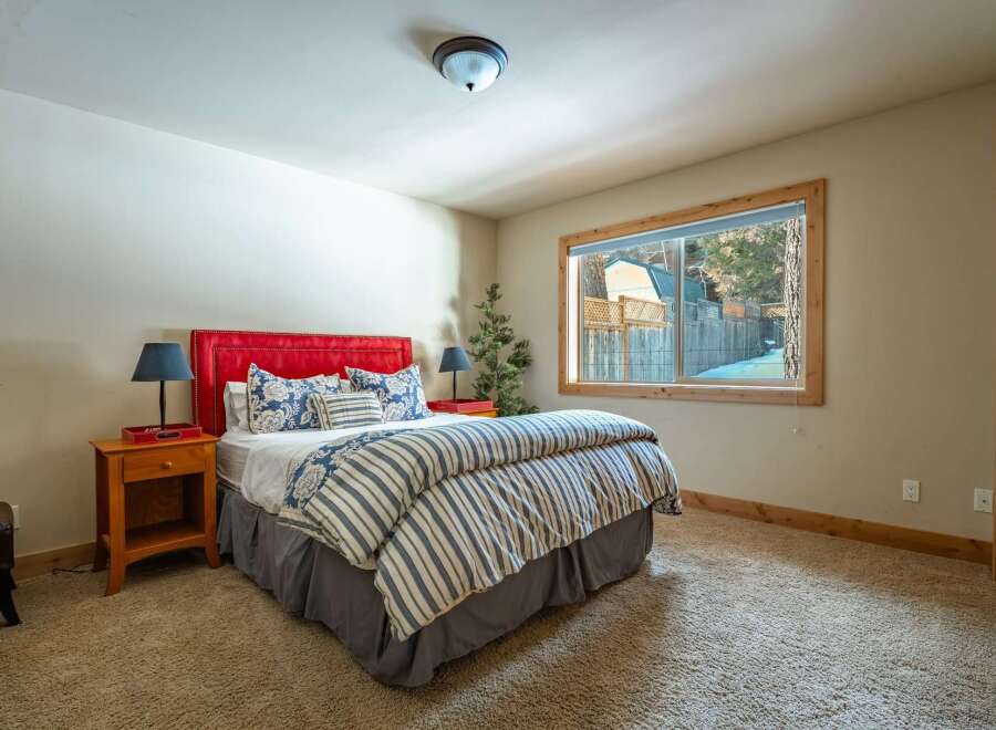 This cozy bedroom features a vibrant red headboard, creating a focal point against the neutral walls.