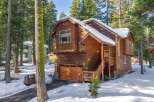 This stunning wooden cabin offers a cozy retreat in a serene, snow-covered setting.