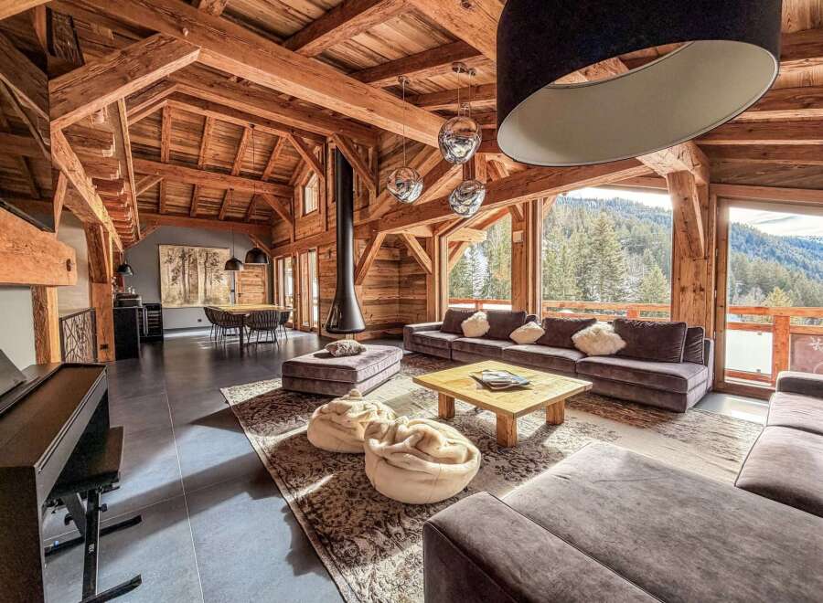 This stunning chalet boasts a warm and inviting interior with exposed wooden beams and a cozy fireplace.