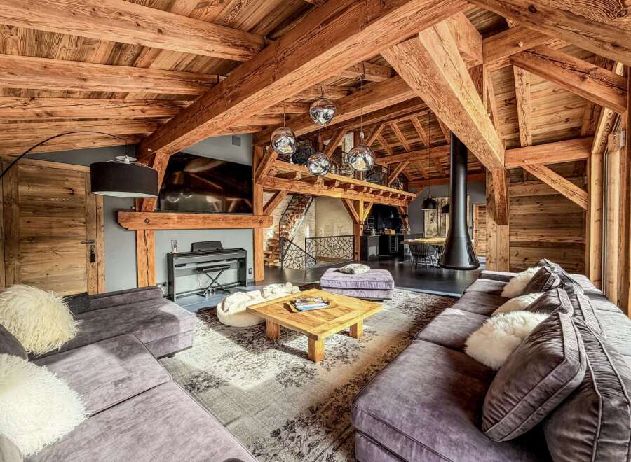 Experience luxury living in this stunning chalet-style home, featuring exposed wooden beams and a cozy fireplace.
