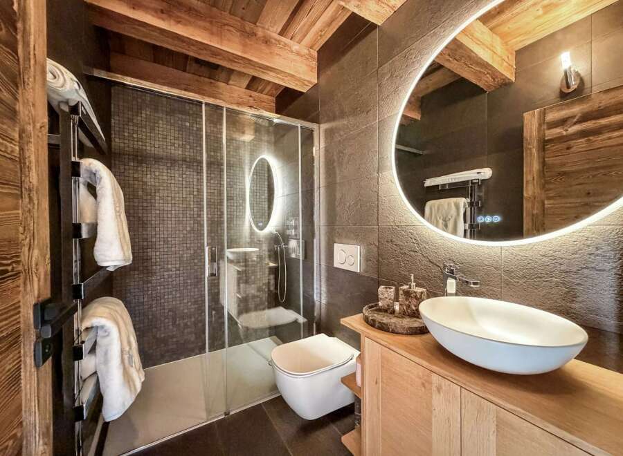 Experience luxury in this stunning bathroom! Featuring a modern design with a sleek glass shower, a stylish sink, and a beautiful wooden vanity.