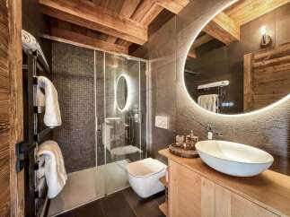 Experience luxury in this stunning bathroom! Featuring a modern design with a sleek glass shower, a stylish sink, and a beautiful wooden vanity.