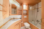 This charming bathroom features a warm, inviting ambiance with its wooden accents and bright white tiles.