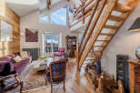 Experience the charm of this stunning property, featuring a cozy living room with a plush purple sofa and a rustic wooden staircase.