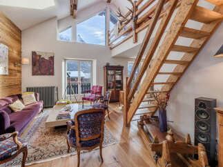 Experience the charm of this stunning property, featuring a cozy living room with a plush purple sofa and a rustic wooden staircase.