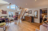 This stunning property boasts a spacious living area with a unique wooden staircase and high ceilings, creating an open and airy atmosphere.