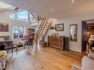 This stunning property boasts a spacious living area with a unique wooden staircase and high ceilings, creating an open and airy atmosphere.