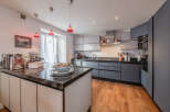 This modern kitchen boasts sleek cabinetry and a stunning black countertop island, perfect for culinary enthusiasts.