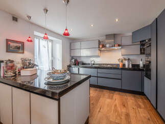 This modern kitchen boasts sleek cabinetry and a stunning black countertop island, perfect for culinary enthusiasts.