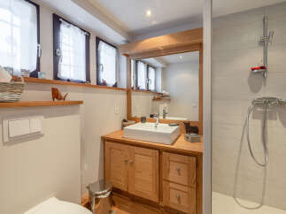 This charming bathroom features a rustic wooden vanity with ample storage, a modern square sink, and a large mirror that reflects natural light.